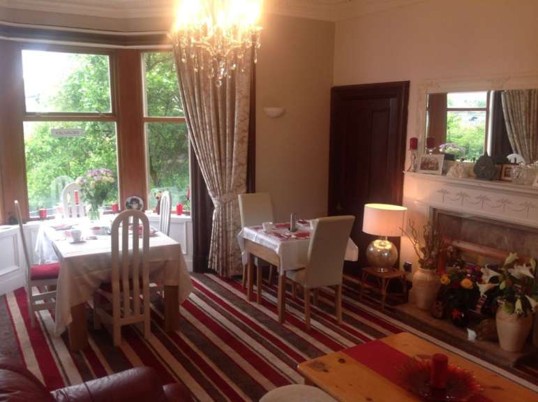 Ein Esszimmer mit zwei gedeckten Tischen, Stühlen und einem Kamin.