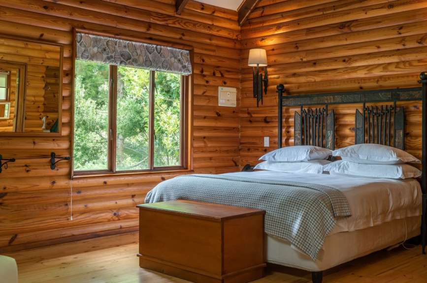 Ein Schlafzimmer in einem Blockhaus mit einem Bett und einem Fenster