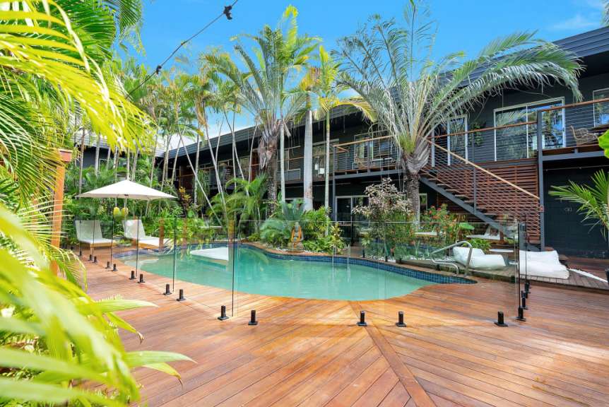 Ein großer Swimmingpool umgeben von Palmen und einem Holzdeck