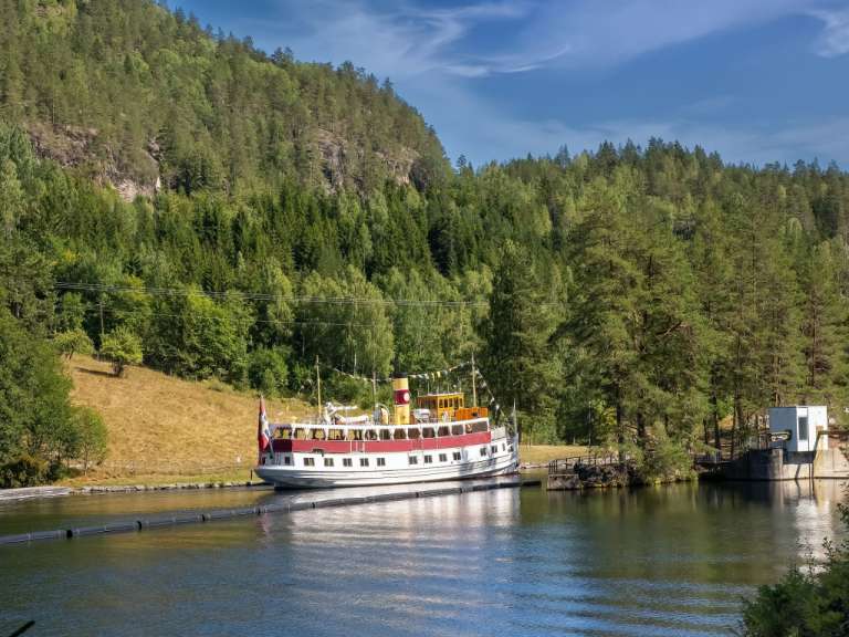 Ein rot-weißes Boot fährt auf einem Fluss
