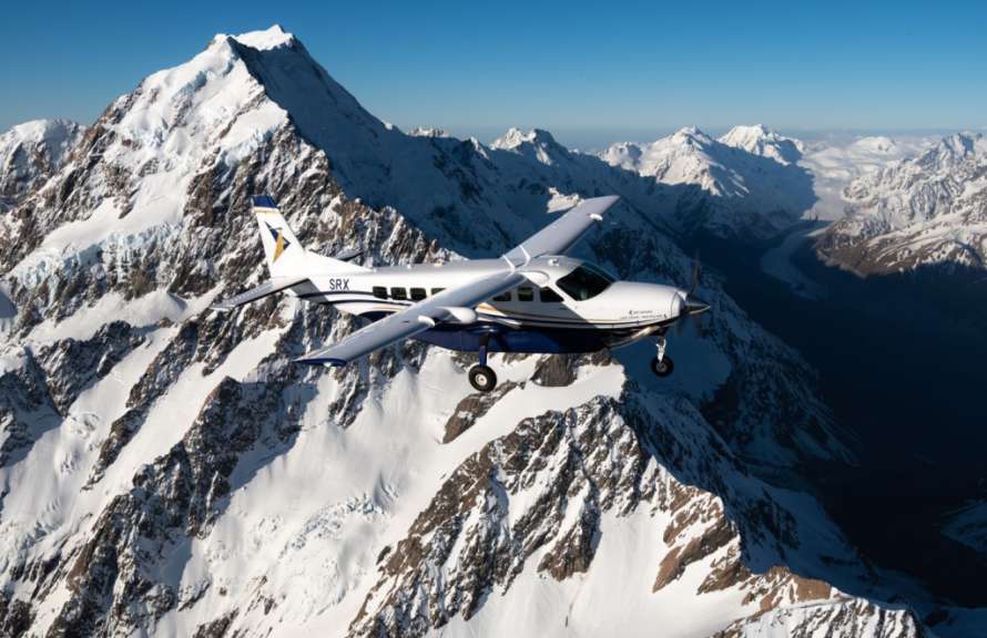 Ein kleines Flugzeug fliegt über einen schneebedeckten Berg