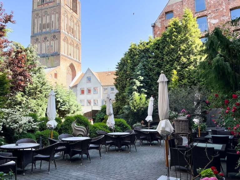 Tische und Stühle in einem Garten mit einem Turm im Hintergrund