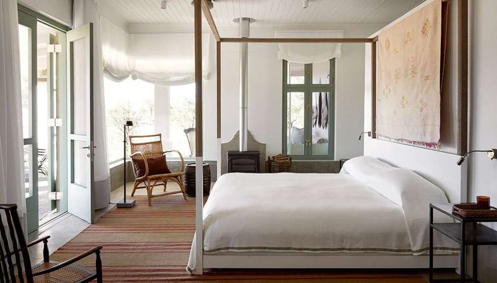 Ein Schlafzimmer mit einem Himmelbett, einem Kaminofen und Zugang zu einem Balkon.