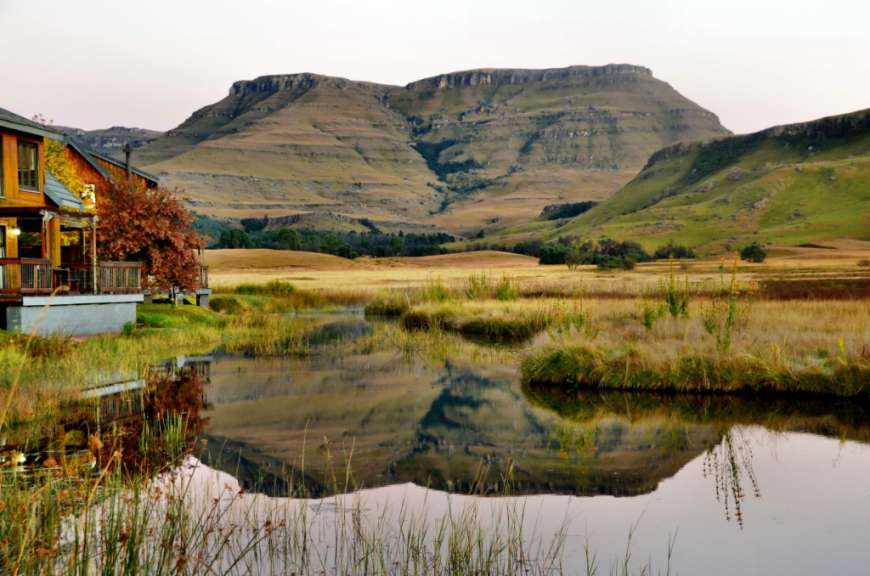 Ein Haus neben einem Teich mit einem Berg im Hintergrund
