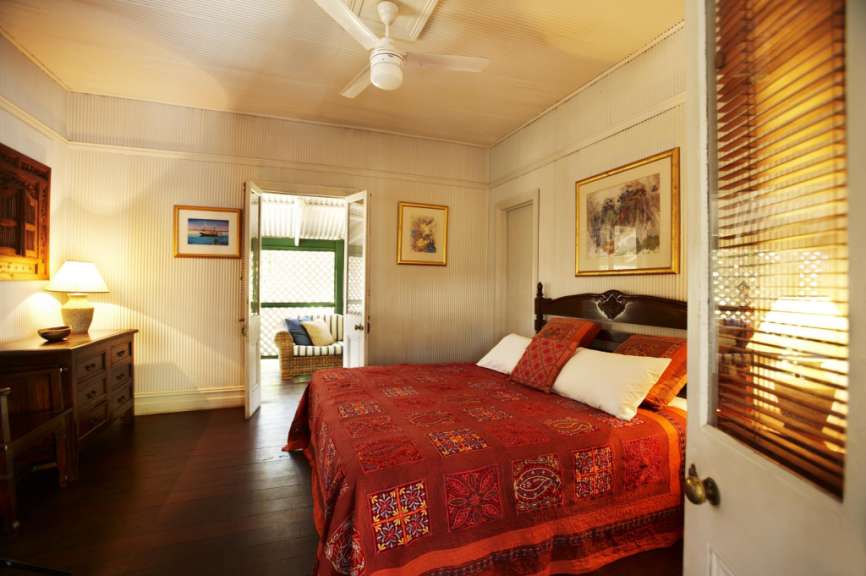 Ein Schlafzimmer mit einem roten Bett und einem Deckenventilator