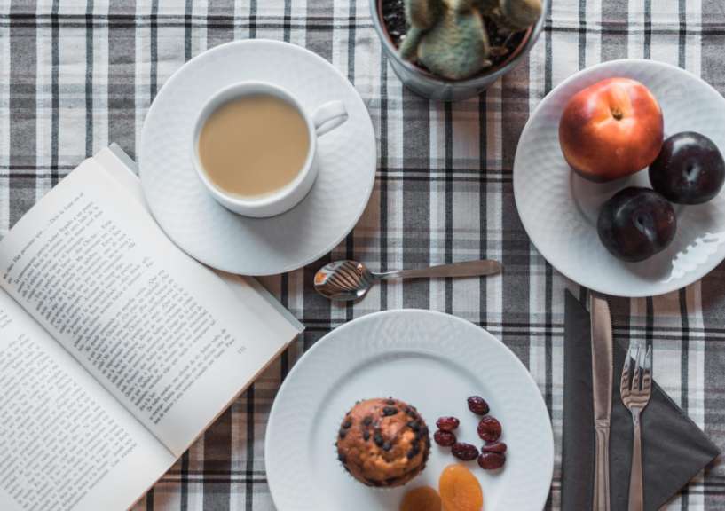 Ein Buch liegt auf einem Tisch neben einer Tasse Kaffee