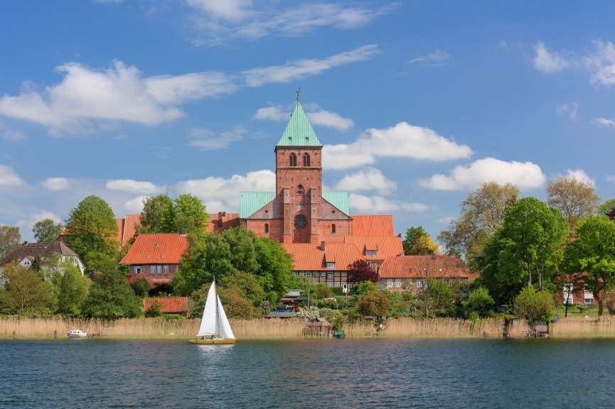 Ein Segelboot schwimmt in einem See vor einer Kirche