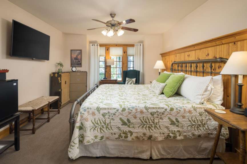 Ein geräumiges Schlafzimmer mit einem großen Bett, einem Fernseher, einem Deckenventilator und einer Kommode.