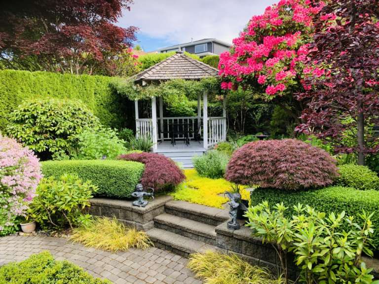 Ein Garten mit einem weißen Pavillon und vielen Blumen