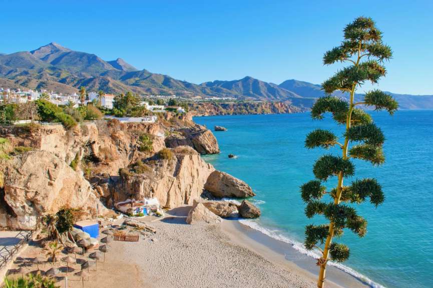 Ein Strand mit Bäumen und Bergen im Hintergrund