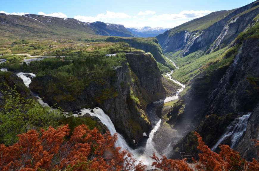 Ein Wasserfall mitten in einem Tal mit Bergen im Hintergrund