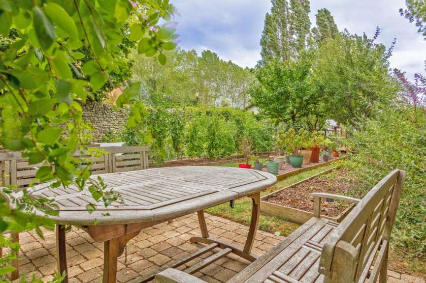 Ein Tisch und Stühle in einem Garten mit vielen Pflanzen