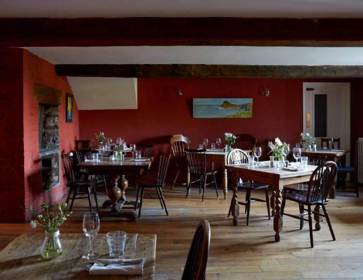 Ein Esszimmer mit Tischen und Stühlen und einem Gemälde an der Wand