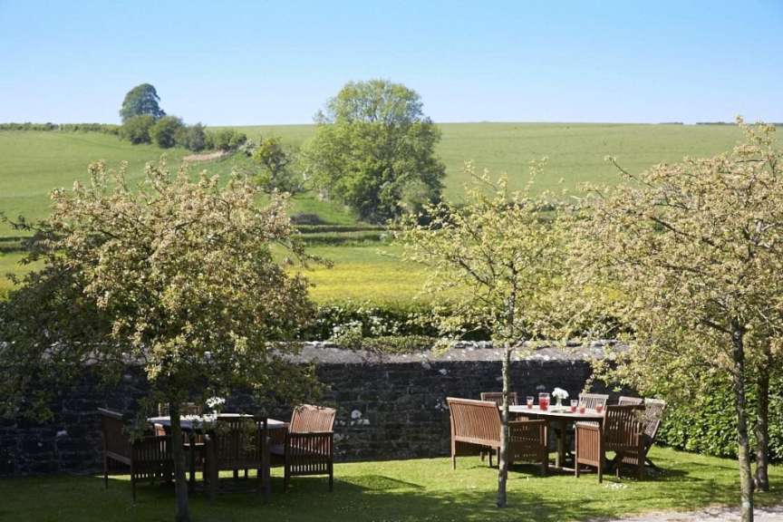 Ein Tisch und Stühle in einem Garten mit Blick auf ein Feld