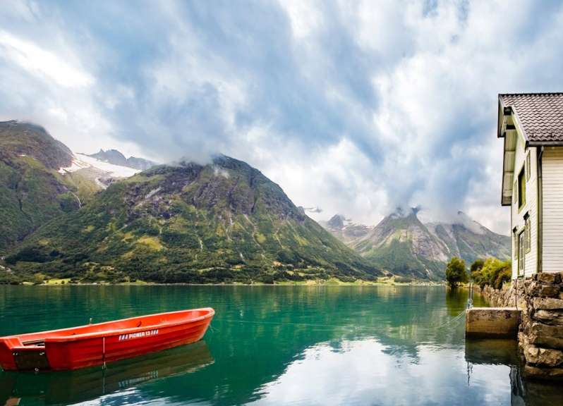 Ein kleines rotes Boot auf einem See mit einem Berg im Hintergrund