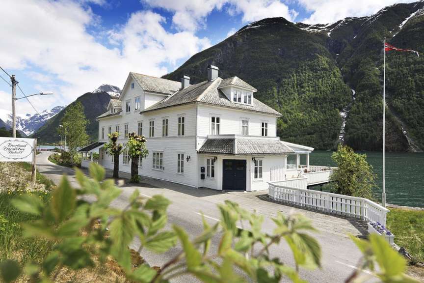 Ein großes weißes Haus mit einem Schild davor, das sagt fjordland hotel