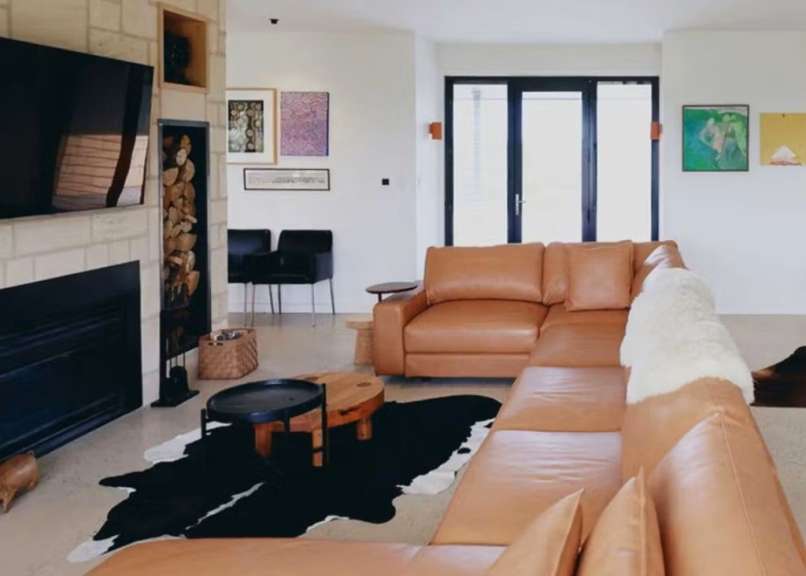 Ein Wohnzimmer mit einem braunen Ledersofa und einem schwarz-weißen Teppich