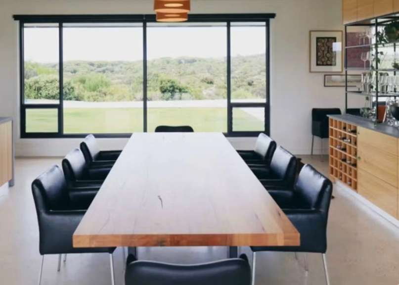 Ein Esszimmer mit einem langen Holztisch und schwarzen Stühlen