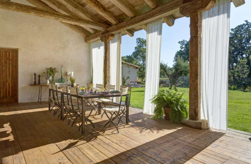 Ein Tisch und Stühle auf einer Veranda mit weißen Vorhängen