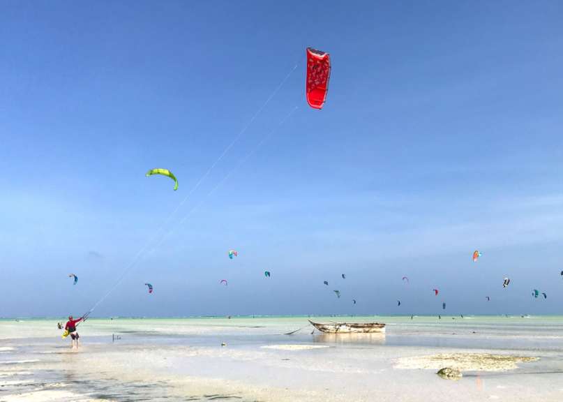 Ein Mann fliegt mit einem roten Drachen am Strand