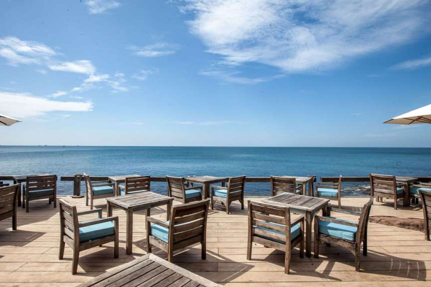 Tische und Stühle auf einem Holzdeck mit Blick auf das Meer