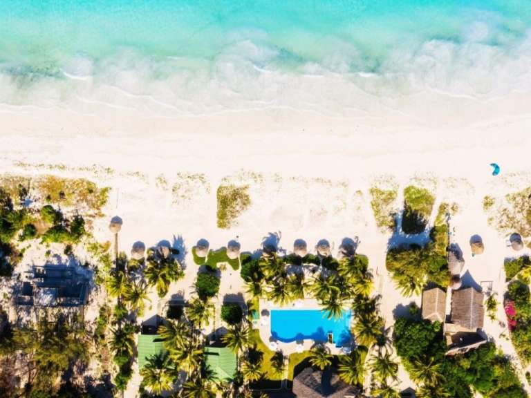 Eine Luftaufnahme eines tropischen Strandes mit einem großen Pool