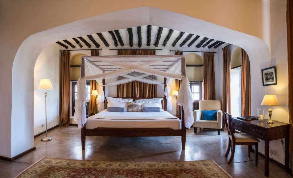 Ein Schlafzimmer mit einem Himmelbett und einem Stuhl