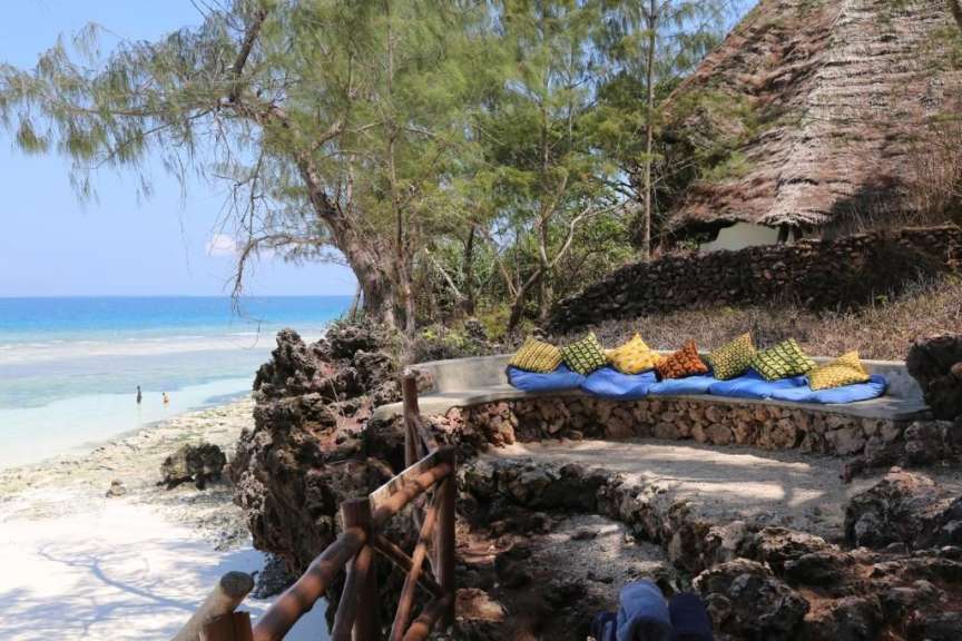 Blaue und gelbe Kissen sitzen auf einer Steinbank am Strand