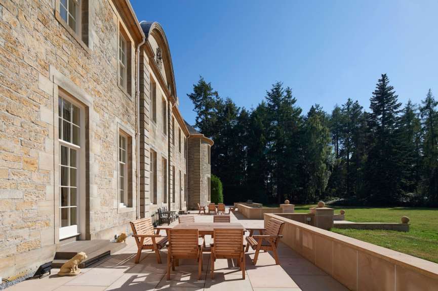 Eine Terrasse mit einem Tisch und Stühlen vor einem großen Steingebäude