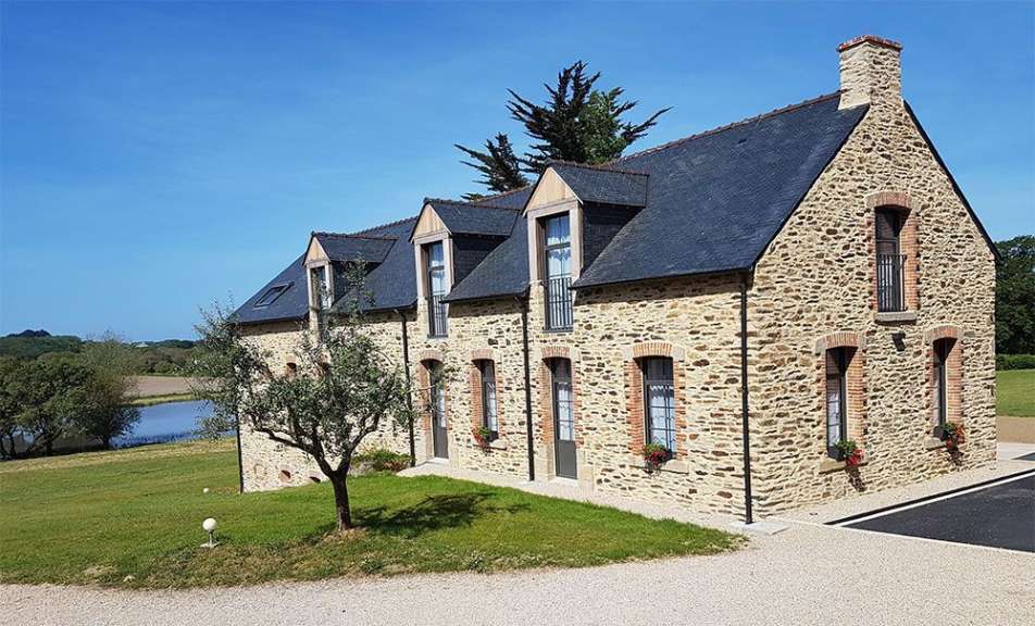 Ein großes Steinhaus mit schwarzem Dach und vielen Fenstern
