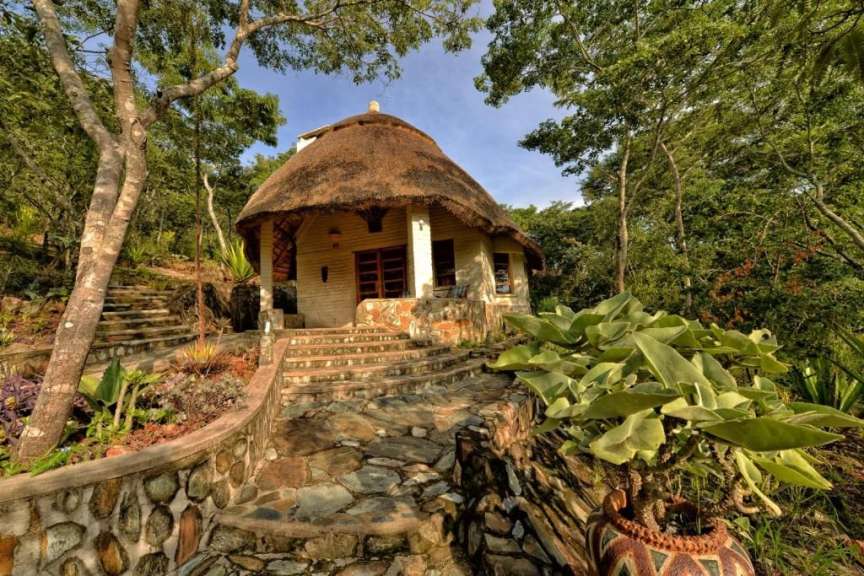 Ein kleines Haus mit Strohdach und Steintreppen