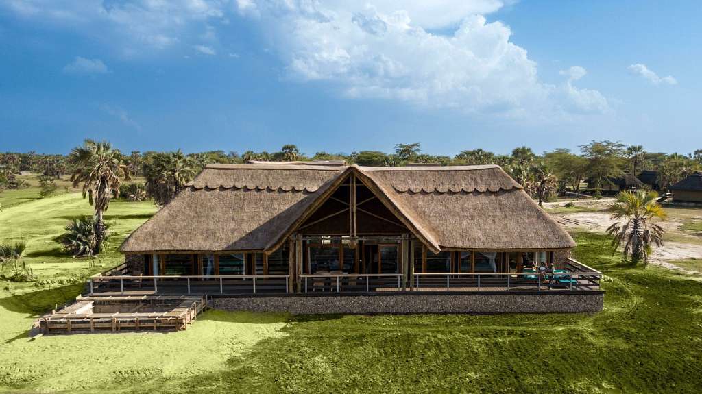 Ein Haus mit Strohdach sitzt auf einer grünen Wiese