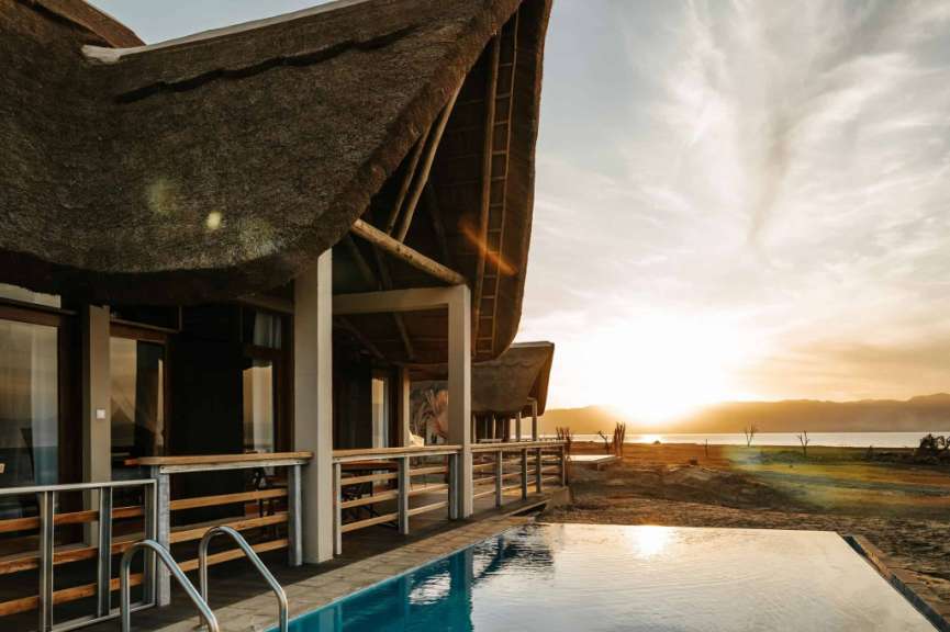 Ein Haus mit Strohdach und einem Pool in der Nähe
