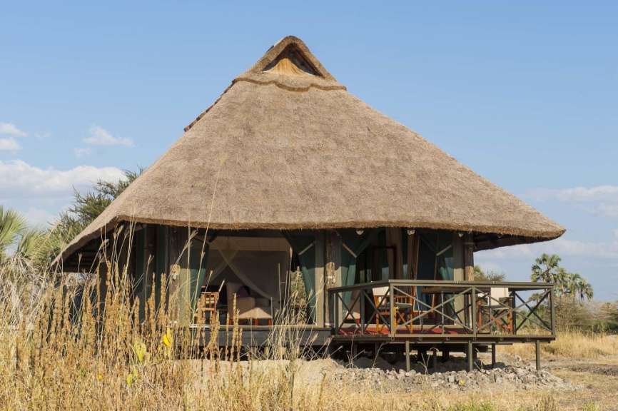 Ein kleines Haus mit Strohdach und einer Veranda