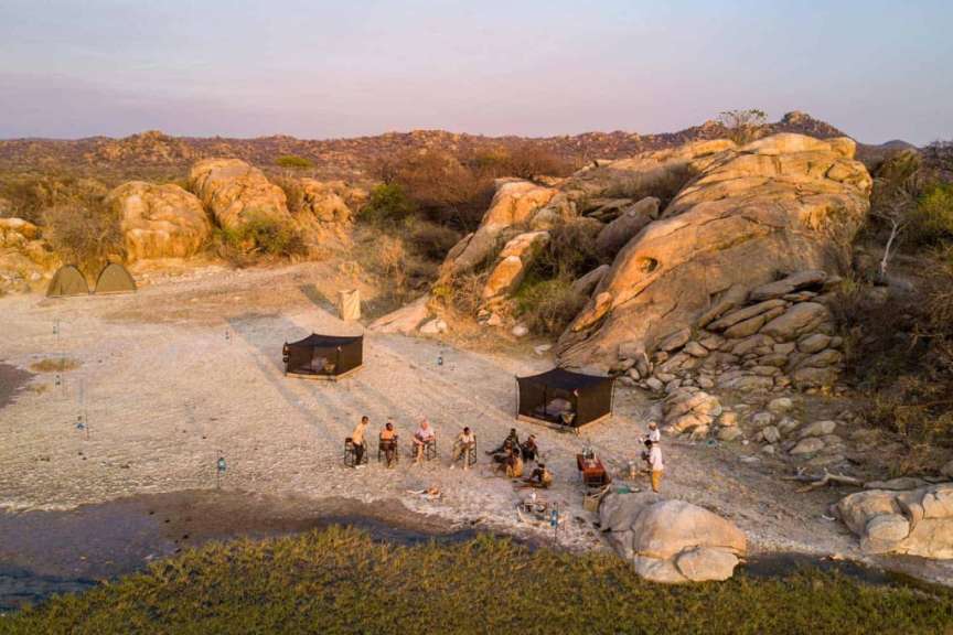 Eine Gruppe von Menschen sitzt auf einem Strand in der Nähe von Felsen
