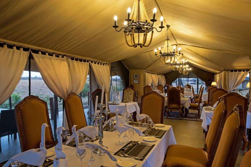 Ein Esszimmer mit langen Tischen und Stühlen und vielen Kronleuchtern