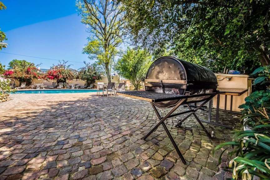 Ein Grill steht auf einem Backsteinterrassen neben einem Pool