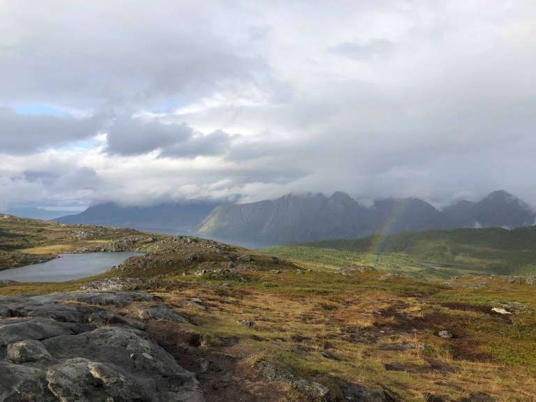 Ein Regenbogen scheint über einen Bergsee in den Bergen
