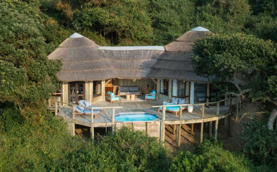 Ein Haus mit Strohdach und einem Pool auf einem Holzdeck