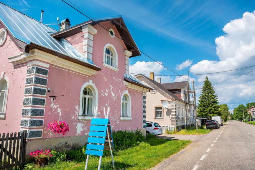 Ein rosa Haus mit einem blauen Schild davor