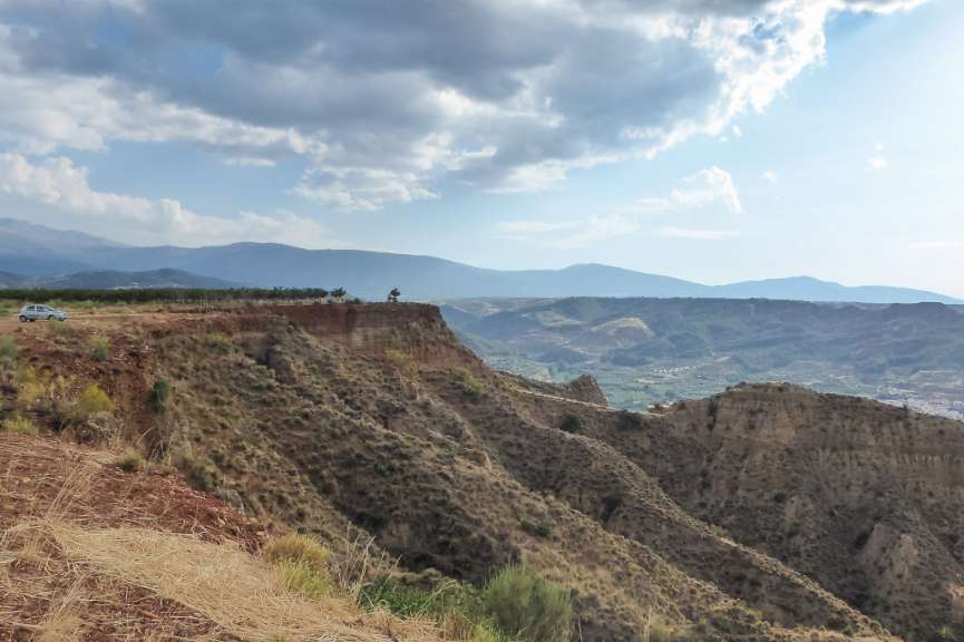 Ein Auto steht auf einer Klippe mit Blick auf die Berge