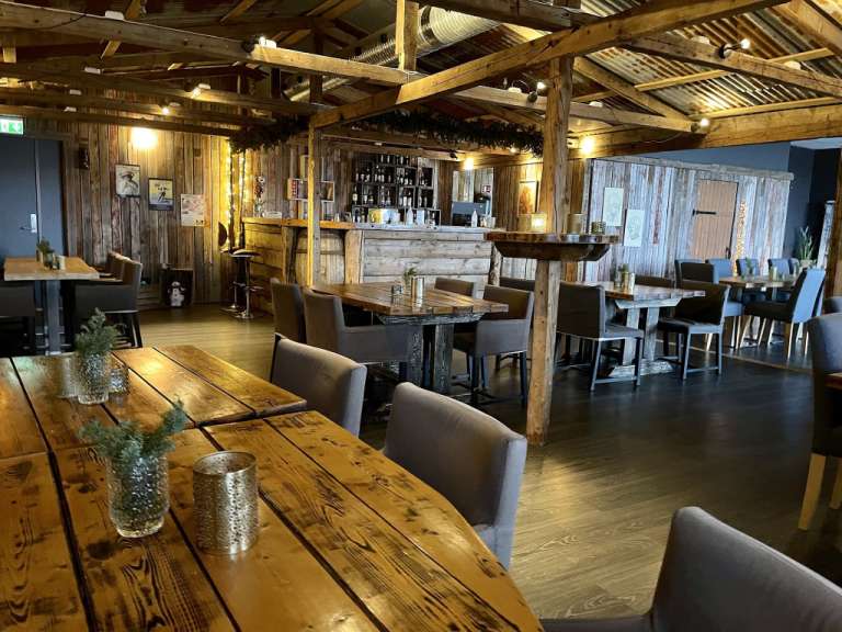 Ein Restaurant mit Holztischen und Stühlen und einer Bar