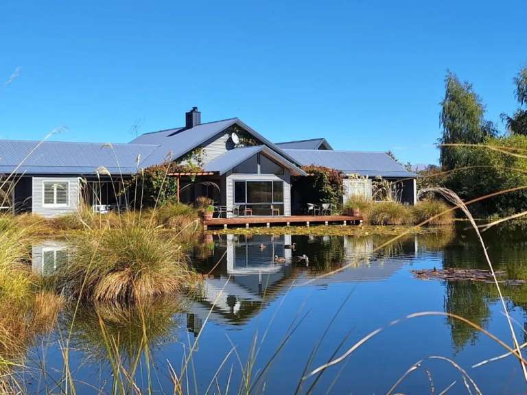Ein Haus steht neben einem Teich mit Enten im Wasser