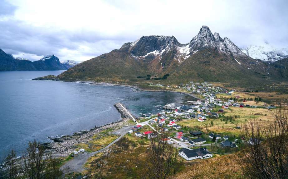 Ein kleines Dorf an der Küste mit Bergen im Hintergrund