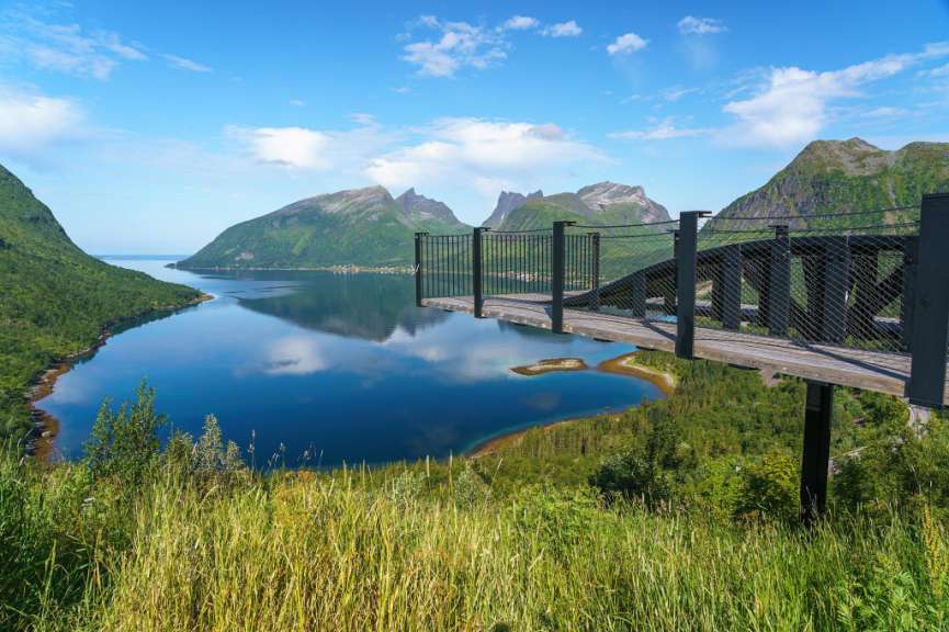 Eine Holzbrücke über einen See mit Bergen im Hintergrund
