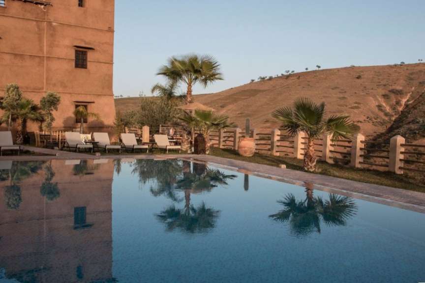 Ein großer Pool mit Liegestühlen und Palmen davor