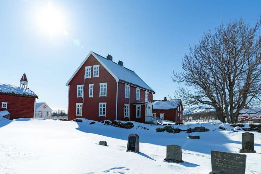 Ein rotes haus mit weißen fenstern steht im schneebedeckten dorf