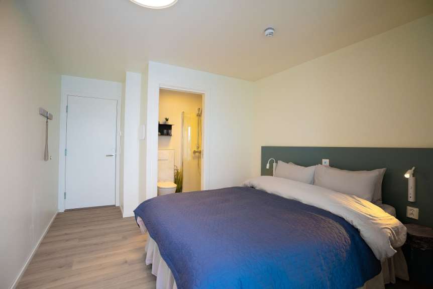 Ein Schlafzimmer mit einem blauen Bett und weißen Kissen