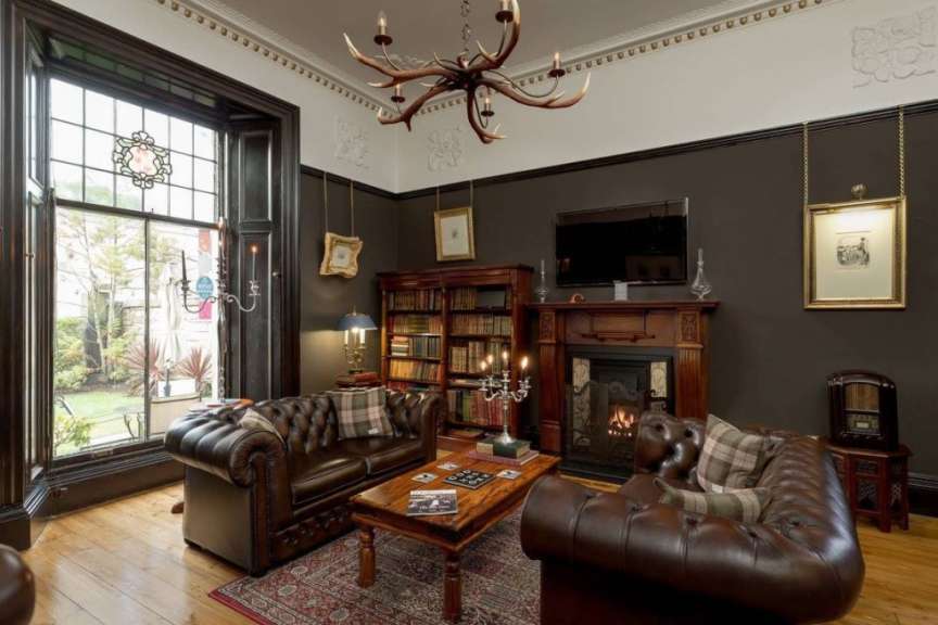 Ein luxuriöses Wohnzimmer mit Ledersofas, einem Kamin und einem Bücherregal.