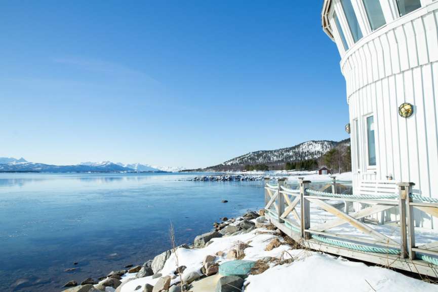 Ein weißes Gebäude neben einem See mit schneebedeckten Bergen im Hintergrund